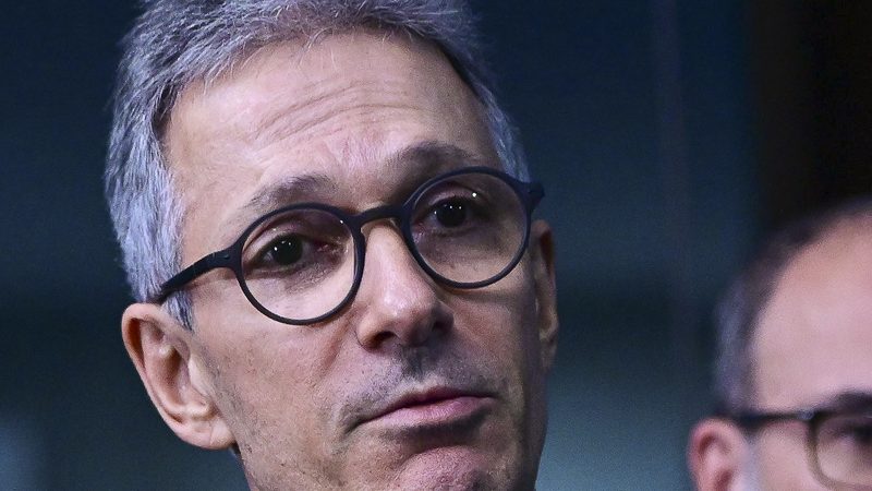 Fotografia. Romeu Zema, de terno escuro, gravata e óculos, fala durante entrevista coletiva no Senado Federal.