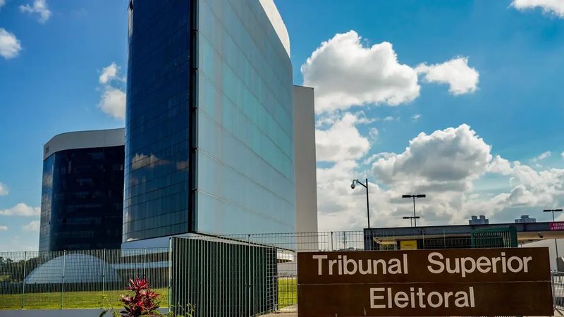 Fotografia. Plenário do Tribunal Superior Eleitoral, com a bancada dos ministros ao fundo e o brasão da República ao centro.